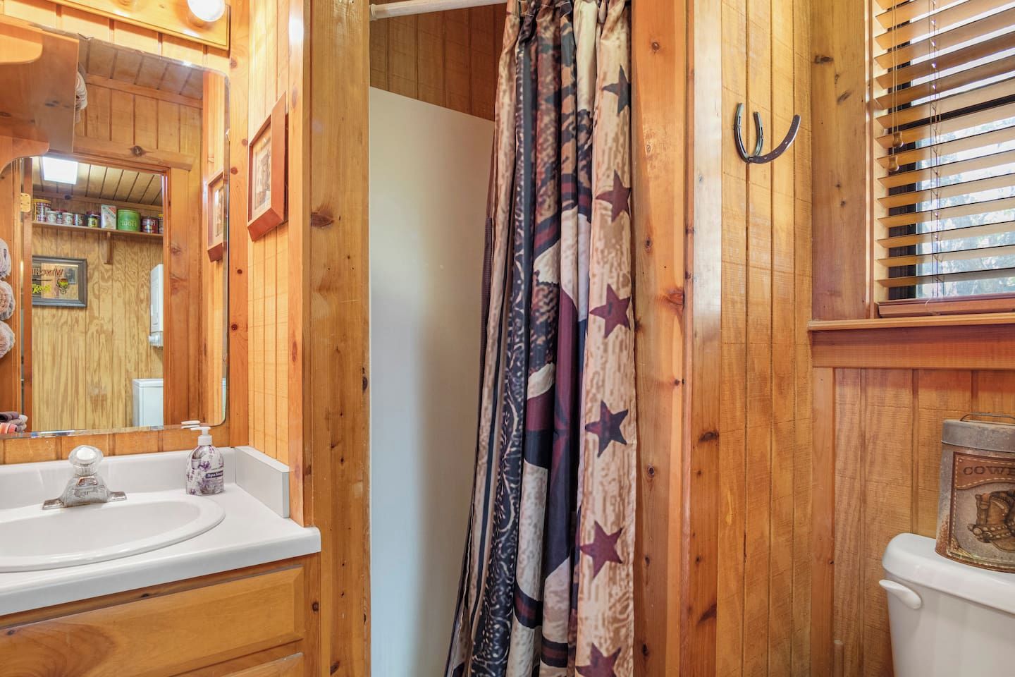 A wooden bathroom with a sink, mirror, and toilet.