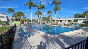 A pool area with lounge chairs, palm trees, and a clear blue sky. - Waterfront Ground Level Condo Only Steps From The Beach  (Englewood)