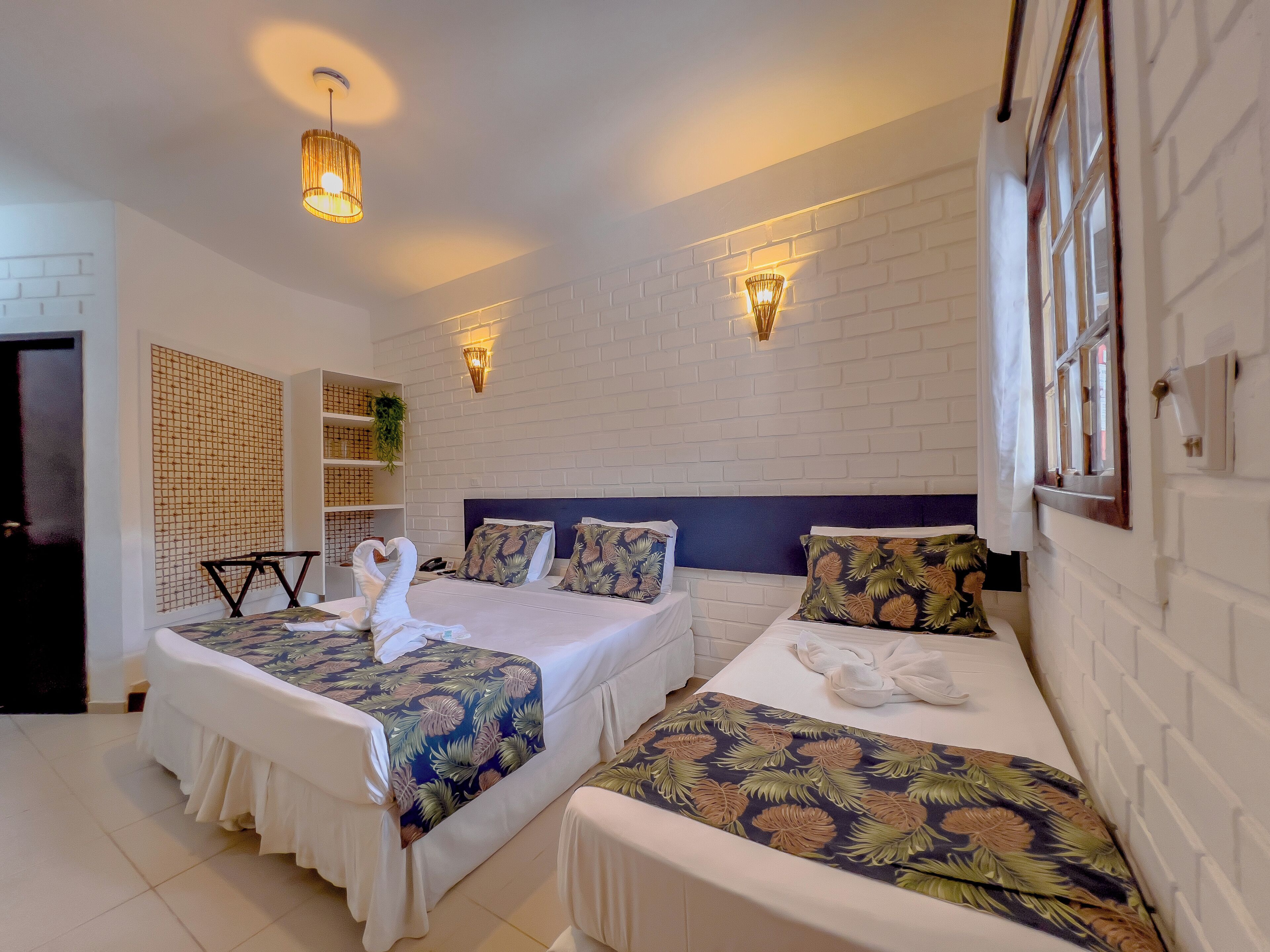 A hotel room with two beds, white walls, and a brick-patterned accent wall.