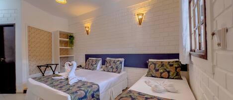 A hotel room with two beds, white walls, and a brick-patterned accent wall.