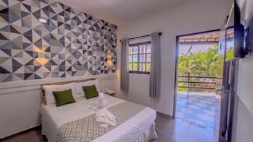 Habitación de hotel con una pared de estampado geométrico, una cama con ropa de cama blanca y almohadas verdes, una mesita de noche y una ventana con cortinas.