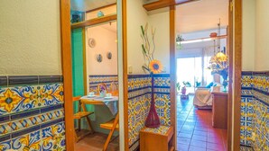 A dining area with a table and chairs, a vase with a flower, and a wall with patterned tiles. - Aquamarine Terrace Apartment by Hello Homes Sitges (Sitges)
