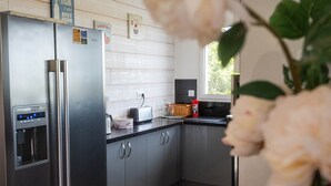 A modern kitchen with stainless steel appliances, grey cabinets, and a window providing natural light. - Ardèche Home - Gite le Nid - Comfortable house with swimming pool, rated 4*. (Tauriers)
