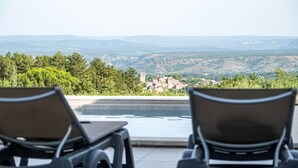 A poolside area with two lounge chairs and a view of a mountainous landscape.
