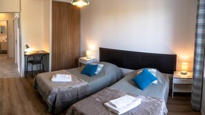 A hotel room with two beds, a desk, and a wardrobe.