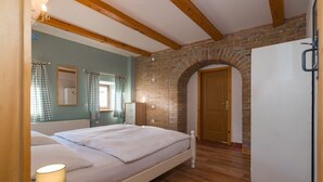Ein Schlafzimmer mit einem Bett, Holzboden, Backsteinwand und einem weißen Kleiderschrank.