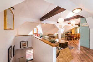 Ein großzügiges Loft mit hohen Decken, freiliegenden Holzbalken und einer gemütlichen Sitzecke mit Tisch und Stühlen.