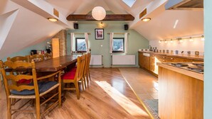 Gemütlicher Essbereich im Dachgeschoss mit Holztisch und -stühlen, eine Küche mit Bar und Blick ins Freie.