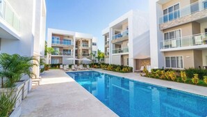 A modern hotel with a central swimming pool, multiple balconies, and outdoor seating areas. - Paseo Del Mar B2B_200Mbps_Pool_Walk to Beach & Dining! (Bavaro-Punta Cana)
