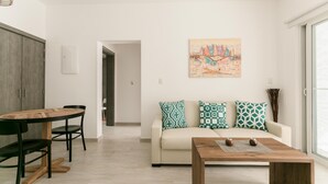A modern living room with a wooden dining table, two black chairs, a beige sofa with patterned cushions, and a wooden coffee table. - Paseo Del Mar B2B_200Mbps_Pool_Walk to Beach & Dining! (Bavaro-Punta Cana)