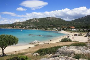 A coastal landscape with a sandy beach, rocky outcrops, and a clear blue sea. - Comfortable air-conditioned apartment 80m from Sant Ambroggio beach (Lumio)