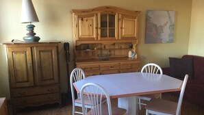 A dining area with a wooden cabinet, a table, and white chairs. - Cozy house in the countryside (Bolandoz)