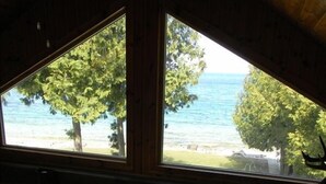 Vue de l’intérieur d’un chalet, donnant sur un espace extérieur avec un foyer et une table de pique-nique.