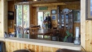 L’intérieur d’un chalet en bois comprend un coin repas, des murs en bois et une grande fenêtre donnant sur un paysage verdoyant.