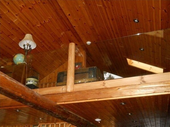 Une chambre mansardée avec des poutres en bois, un globe terrestre et une lampe.