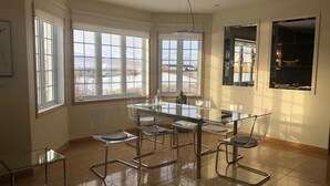 A modern kitchen with a glass dining table and chairs, large windows, and a view of the outdoors. - Villa Mafini (Akureyri)
