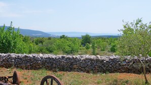 Un mur de pierre offrant une vue sur un paysage verdoyant et des montagnes lointaines.