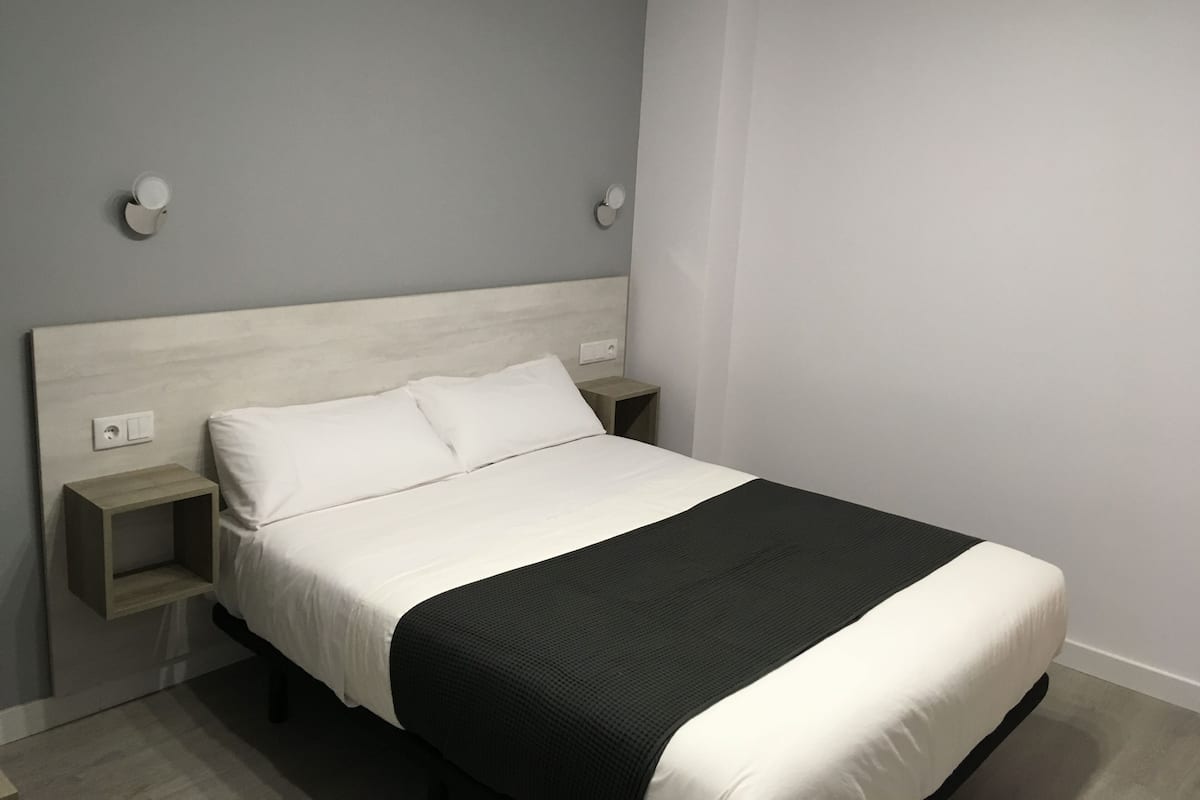 Escritorio, cortinas blackout y tabla de planchar con plancha