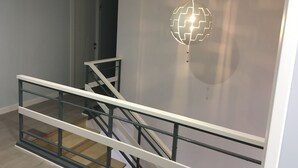 A staircase with a white railing, a wall-mounted spherical light fixture, and a door in the background. - Hostal I Dream Salamanca (Salamanca)