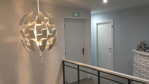 A hallway with a modern spherical light fixture, a white door, and a white storage unit with drawers. - Hostal I Dream Salamanca (Salamanca)