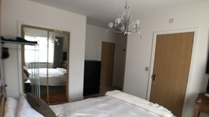 Une chambre à coucher avec un lit, une commode, un miroir et un lustre.