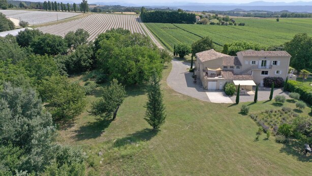 Ein großes, eingeschossiges Haus mit Ziegeldach, umgeben von gepflegten Gärten und Weinbergen.