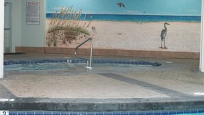 Zona de spa con un mural de una playa, una bañera de hidromasaje y un ventilador de techo.