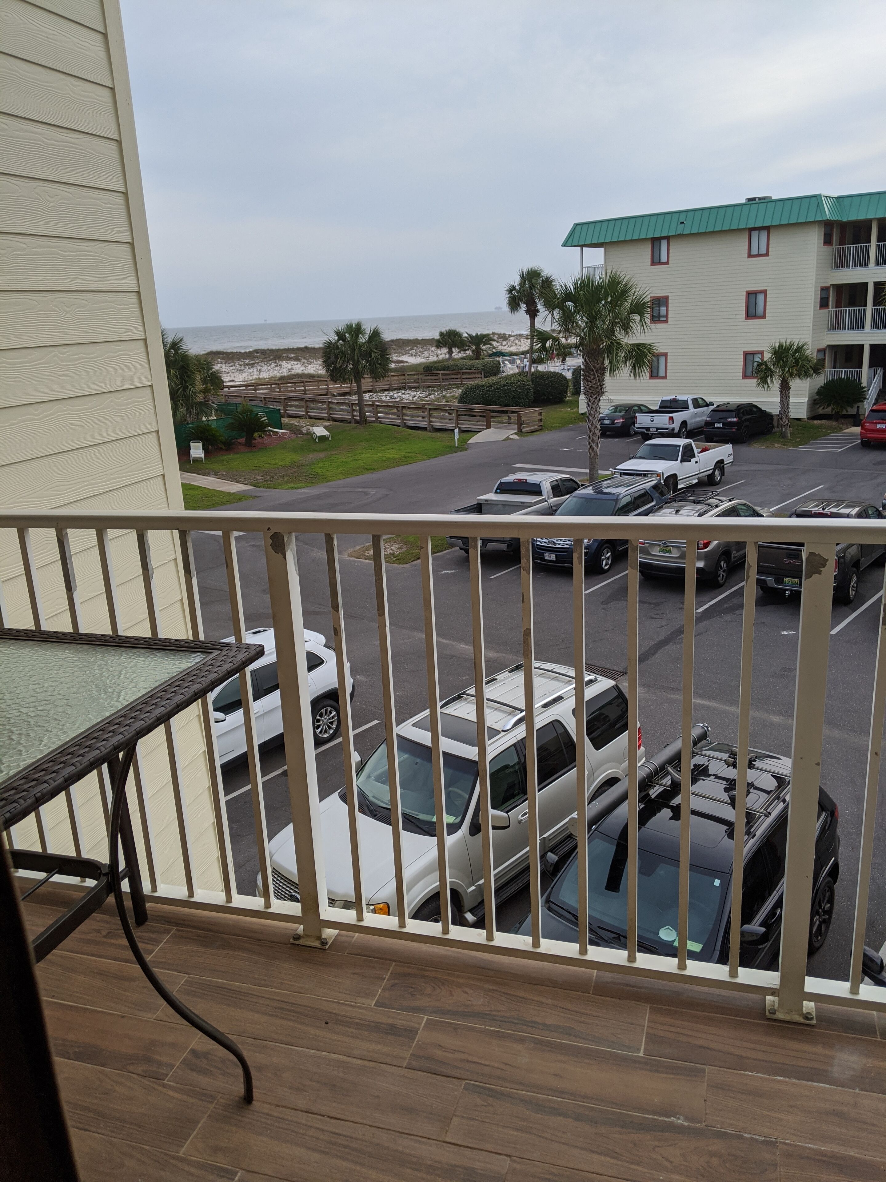 A balcony with a view of a parking lot and a building with a green roof.