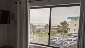 Habitación de hotel con cama, ventana que da a un estacionamiento y un edificio enfrente.