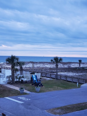 Enjoy the ocean view from this beachfront property, featuring a paved walkway and a comfortable chair.
