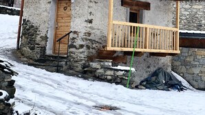 A rustic mountain cabin with a wooden balcony, stone walls, and a sign indicating its location. - Charming individual chalet (tignes les brevieres)