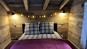 A cozy bedroom with a wooden ceiling, a plaid bedspread, and a purple blanket. - Charming individual chalet (tignes les brevieres)
