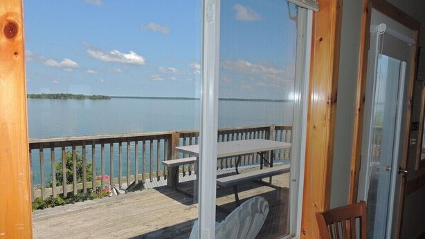 A wooden deck with a view of a calm lake and distant land.