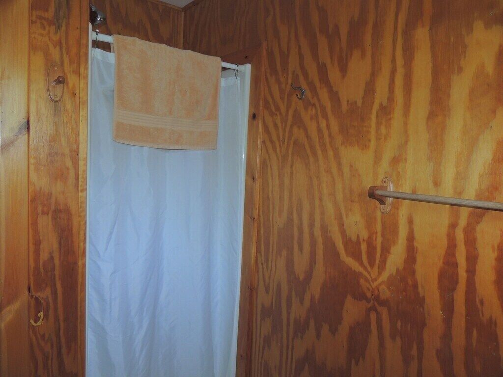 A wooden interior with a white shower curtain and a towel hanging on a metal rod.
