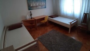 Ein Zimmer mit einem Bett, einem Schreibtisch, einem Sessel, einem Teppich und einem Bild an der Wand.