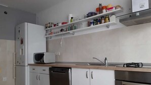 Eine kompakte Küche mit weißen Schränken, einem Geschirrspüler, einer Mikrowelle und einem Edelstahlbackofen.