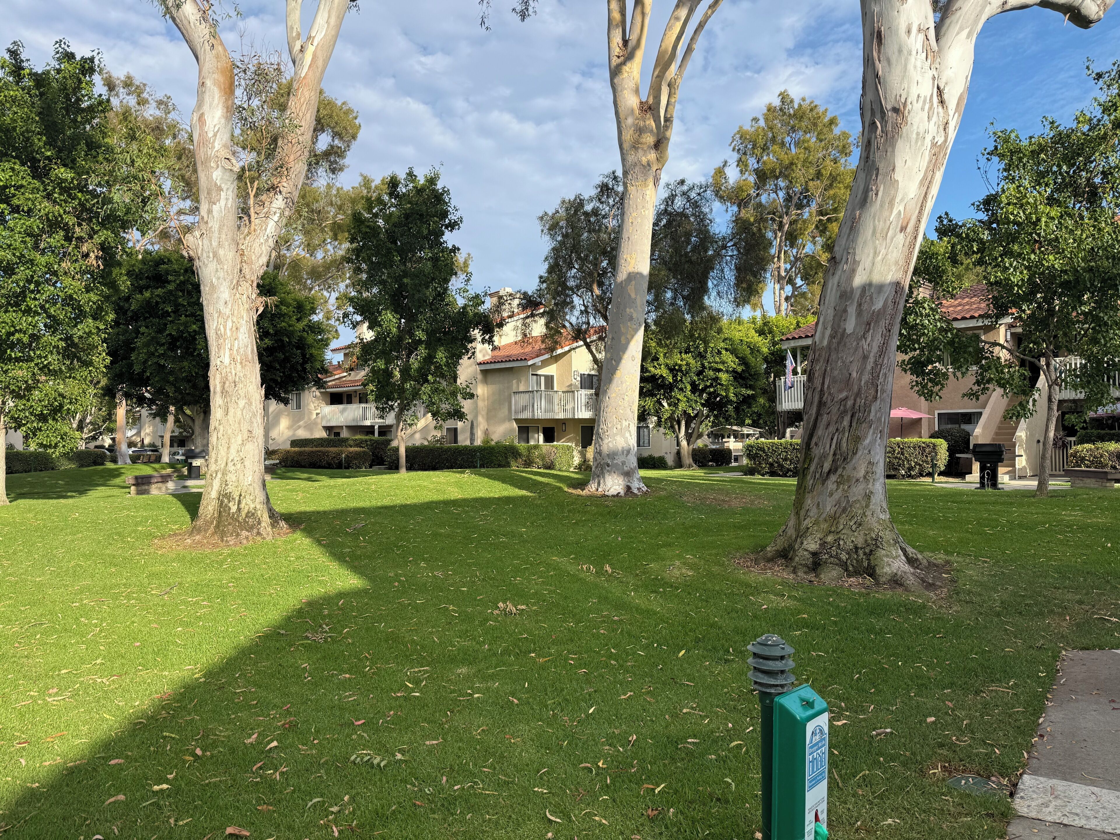 Zona residencial con edificios de varios pisos, césped cuidado y árboles.