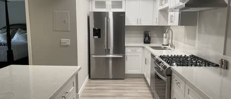 A modern kitchen with stainless steel appliances, white cabinetry, and a central island.