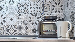 A kitchen with a coffee maker and toaster on the counter, and patterned tiles on the wall. - Manuela Apartments 1 Piazza del Plebiscito - Centro (Napoli)