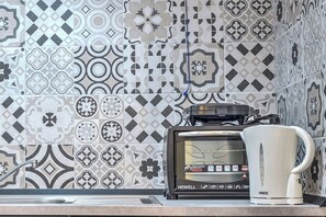 A kitchen with a coffee maker and toaster on the counter, and patterned tiles on the wall.