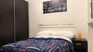 Un dormitorio con cama, mesita de noche, un cuadro en la pared y armario.