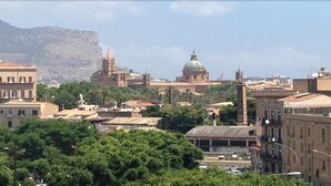 Un paisaje urbano con un edificio histórico destacado, que cuenta con una cúpula y un campanario.