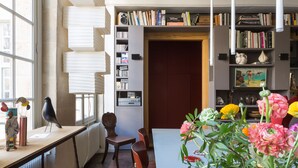 A room with a long table, chairs, a bookshelf, and a window with blinds. - Beautiful Loft on Rue Quincampoix, by Veeve (Paris)