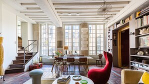 A spacious living room with a staircase, a dining area, and a bookshelf. - Beautiful Loft on Rue Quincampoix, by Veeve (Paris)