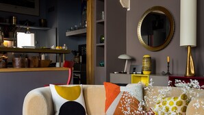 A modern living room with a sofa, coffee table, and decorative items. - Beautiful Loft on Rue Quincampoix, by Veeve (Paris)