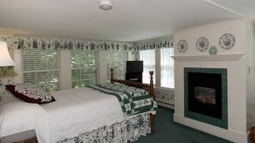 A bedroom with a bed, a fireplace, and a television.