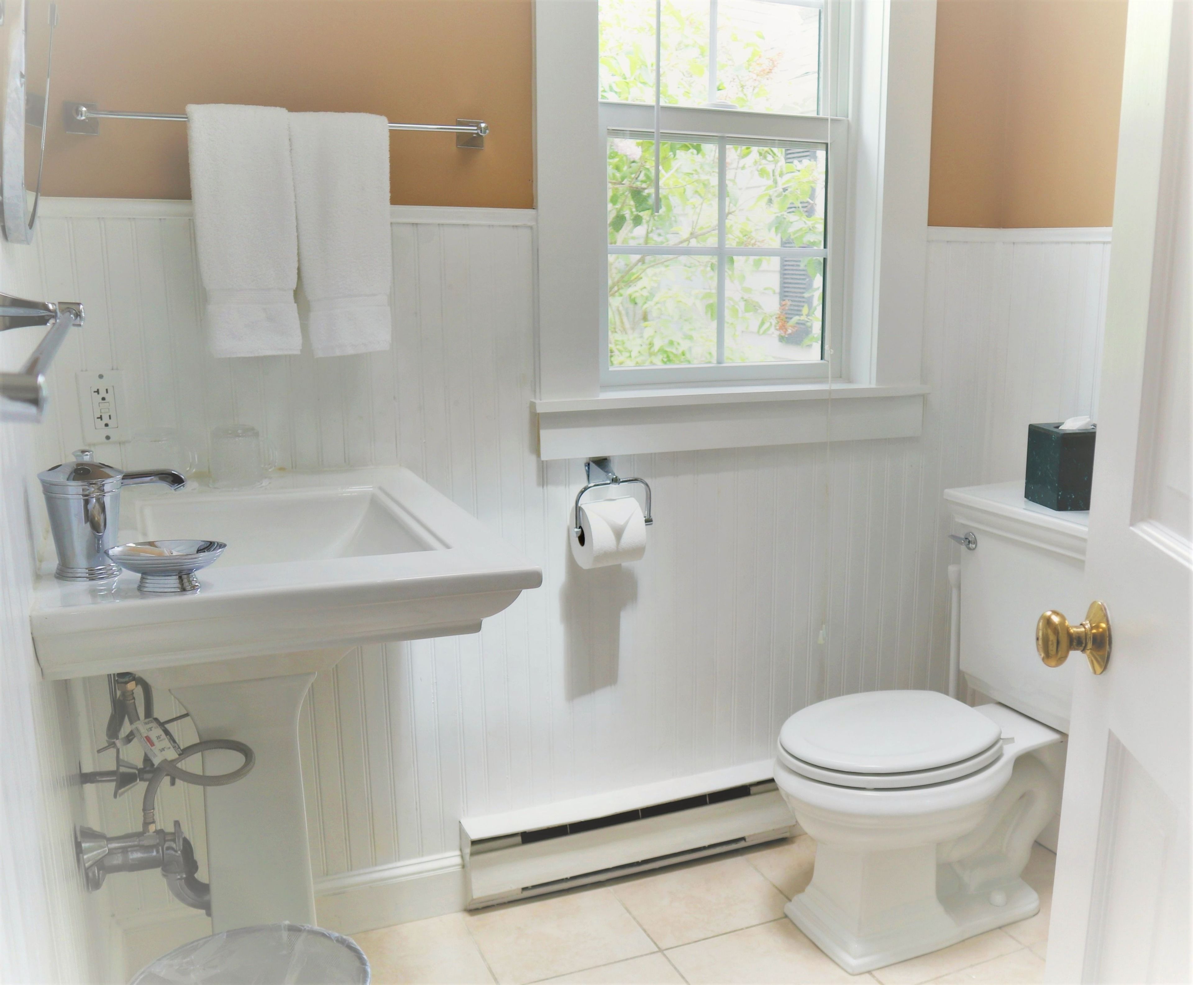 Un baño con lavamanos blanco, inodoro y ventana.