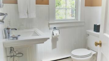 Un baño con lavamanos blanco, inodoro y ventana.