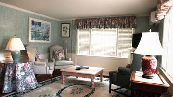 A living room with a floral-patterned rug, a coffee table, a sofa, and a chair.
