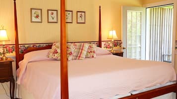 Una cama con dosel, ropa de cama floral, cabecera de madera y dos mesitas de noche con lámparas.